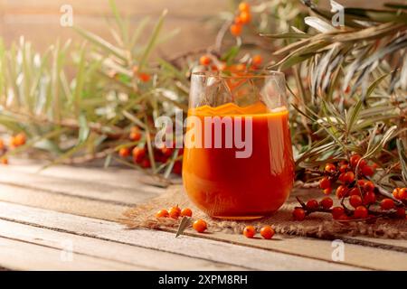 Glass of sea buckthorn juice with fresh berries on an old wooden table. Healthy and diet food. Copy space. Stock Photo