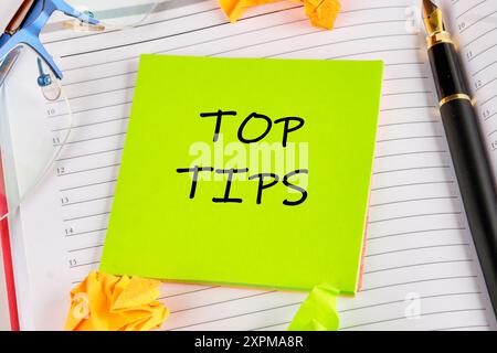 Top tips. Inscription TOP TIPS word on a light green sticker lying on the notebook Stock Photo