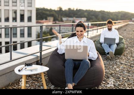 Young professionals working on laptops on rooftop terrace Stock Photo