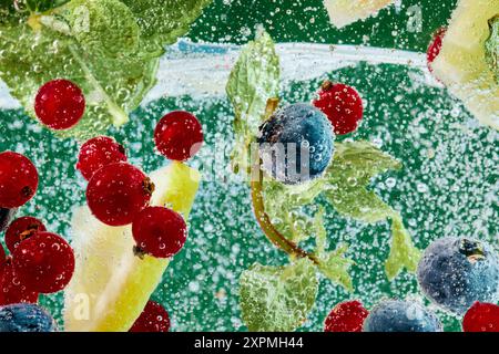 Berries and leaves immersed in sparkling water, surrounded by bubbles, creating vibrant, refreshing scene with green backdrop. Textured wallpaper. Stock Photo