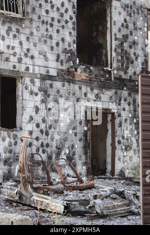 Burnt house and car on backyard. Destroyed building after Russian invasion, Ukraine. War in Ukraine. Abandoned damaged home and burnt auto. Stock Photo