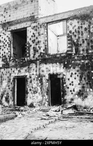 Burnt house, monochrome. Destroyed building after Russian invasion, Ukraine, black and white. War in Ukraine. Abandoned damaged home. War disaster. Stock Photo