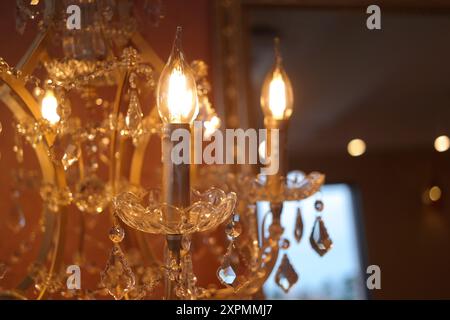 Crystal chandelier with burning candles in the interior of the room Stock Photo