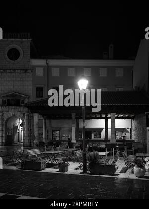 Cres, Croatia - October 23, 2022: Street in Cres with old streetlamps during night, black and white Stock Photo