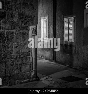 Cres, Croatia - October 23, 2022: Narrow street corner in Cres during night, black and white Stock Photo