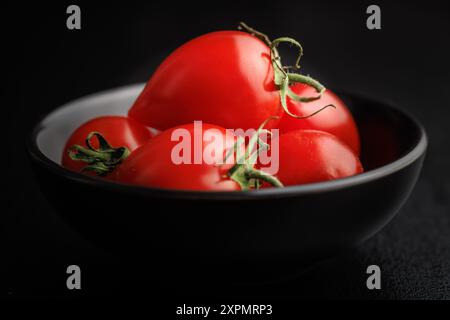 Red cherry tomatoes in bowl on a black table. Stock Photo