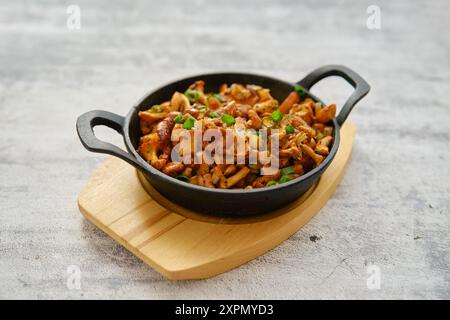 Wild chanterelle mushrooms roasted with thyme and spring onion in a frying pan Stock Photo