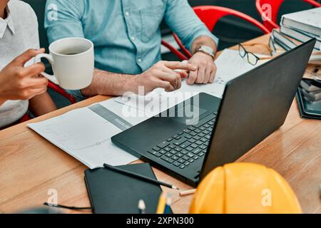 Hands, architect and reading on laptop with people in morning with coffee, decision or design. Partner, tea cup and computer for review with Stock Photo