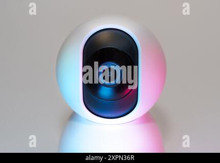 Smart home security camera lens. White device neon pastel lights. Stock Photo