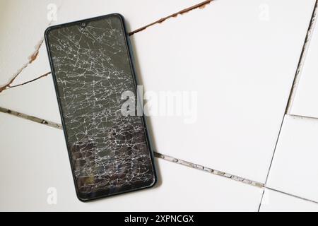 Smartphone with broken screen on the cracked floor Stock Photo