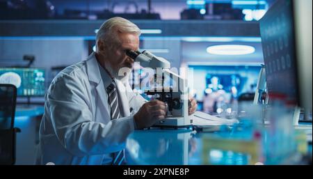 Medical Development Laboratory: Senior Caucasian Male Scientist Using Microscope, Analyzes Petri Dish Sample. Big Pharmaceutical Lab Conducting Biotechnology Research, Developing Innovative Drugs. Stock Photo