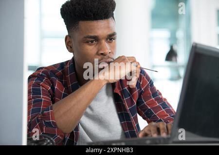 young man works on his laptop and holding a screwdriver Stock Photo