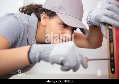 happy female builder using a screwdriver on a door Stock Photo