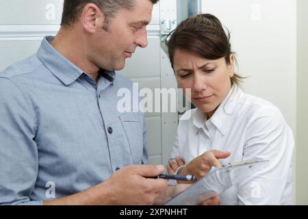 young man and woman discussing something on clipboard Stock Photo