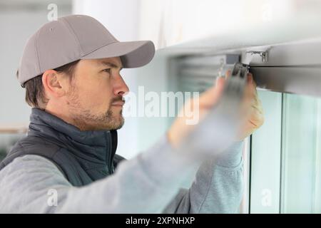 man installing window shades at home Stock Photo