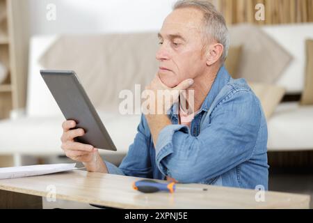 waist up portrait of senior carpenter using tablet Stock Photo