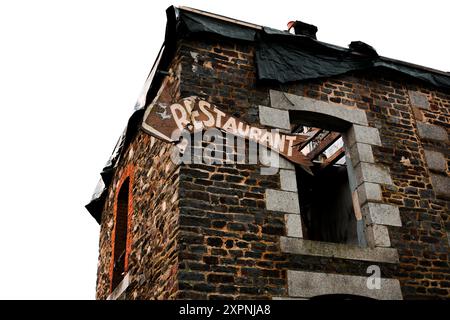 A low angle shot of dilapidated brick building with a broken restaurant sign hanging on the wall Stock Photo