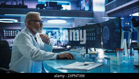 Senior Male Neuroscientist Using Desktop Computer To Analyze MRI Scans Of Brain In Medical Research Center Laboratory. Caucasian Surgeon Studying CT Scan Of Patient Suffering From Brain Tumor. Stock Photo