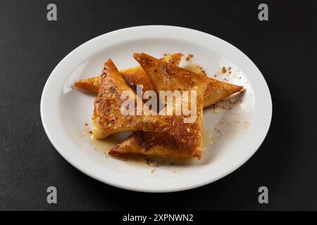 Mini cheese pies with myzithra, cretan honey and cinnamon on white plate. Stock Photo