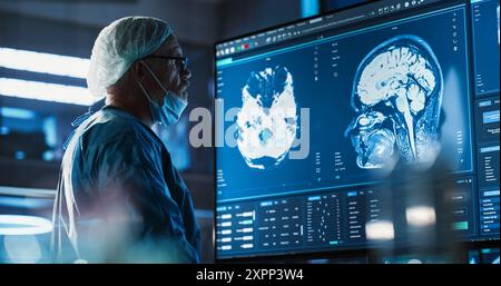 Medical Hospital Research Laboratory: Caucasian Male Neurosurgeon Looking At TV Screen With Brain MRI Scans Of Patient, Analyzing, Preparing For Complicated Neurosurgery, Wearing Surgical Gown. Stock Photo