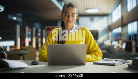 Focused Young Teacher Preparing for Class in a Library Reading Hall. Successful Female Using Laptop Computer to Work on a University Research Project, Writing Down Ideas in Notebook Stock Photo