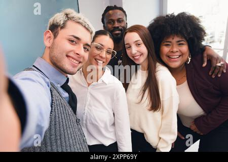 Selfie portrait photo of multiethnic and multiracial business team standing in office after work, mobile phone camera perspective, small group of smil Stock Photo
