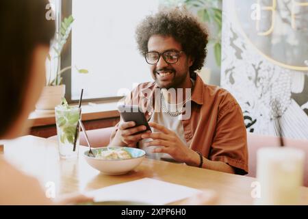 Smiling Young Man Using Smartphone at Restaurant Stock Photo