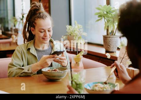 Smiling Woman Using Smartphone in Cozy Restaurant Setting Stock Photo