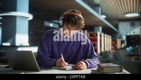 Thoughtful Young Student Preparing for Class, Doing Homework on a Laptop Computer. Freelance Journalist Working on an Article in a Public Library with Modern Simple Interior Stock Photo