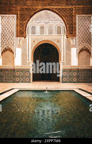 The intricate Moroccan architecture with ornate designs and a tranquil pool in the foreground Stock Photo