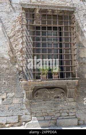 detail of grating on window  of monumental facade of historical building, shot  in bright summer light at Narni, Umbria, Italy Stock Photo