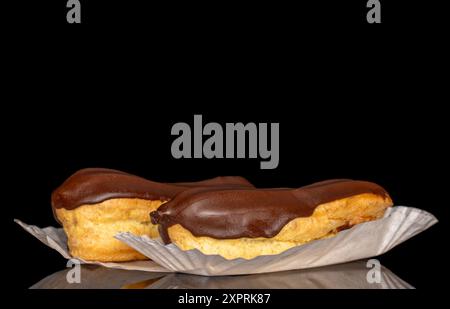 Two eclairs with cream, macro, isolated on a black background. Stock Photo