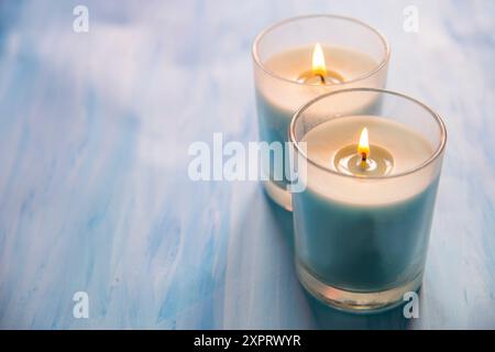 Two lit up candles on blue surface. Stock Photo
