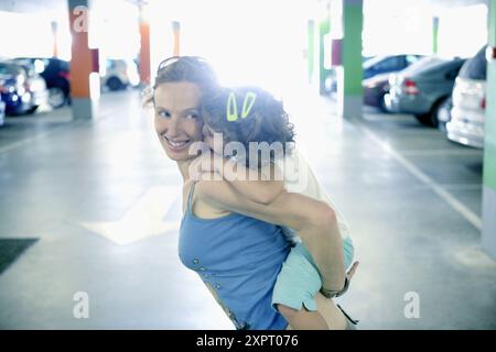 Woman holding her daughter in a car parking Stock Photo