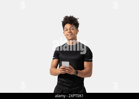 Young Man Smiling While Holding Smartphone in Studio Stock Photo