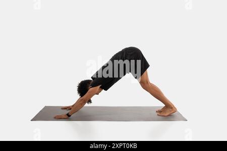 Man Practicing Downward Facing Dog Yoga Pose in Studio Stock Photo