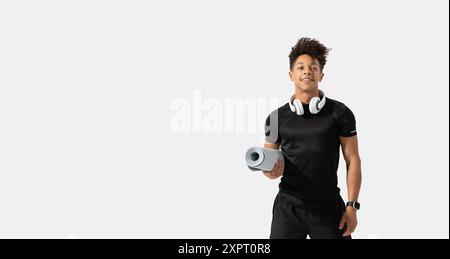 Young Man Holding Yoga Mat While Wearing Headphones Stock Photo