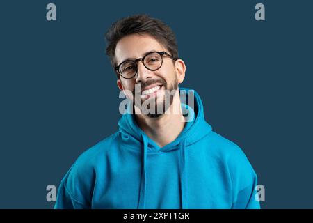 Young Man Smiling Warmly While Wearing a Blue Hoodie Stock Photo