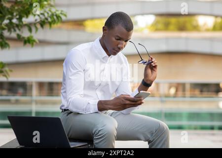 Young Man Engaged in Thoughtful Reflection While Using Smartphone Stock Photo