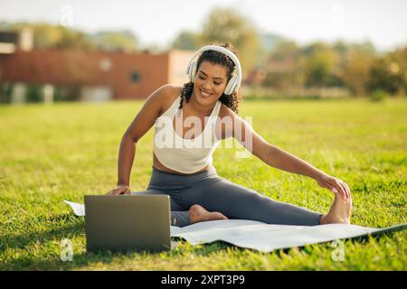 Young Woman Practicing Yoga While Listening to Music Outdoors Stock Photo