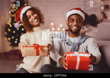 Happy New Year! Afro couple stretching gift boxes Stock Photo