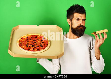 Bearded man with delicious pizza in cardboard box. Italian food. Fast food restaurant, pizzeria advertising. Pizza delivery. Takeaway pizza. Serious m Stock Photo