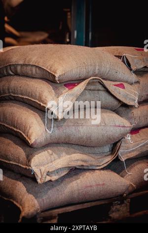 Stacks of burlap sacks full of coffee beans are stored in a warehouse Stock Photo