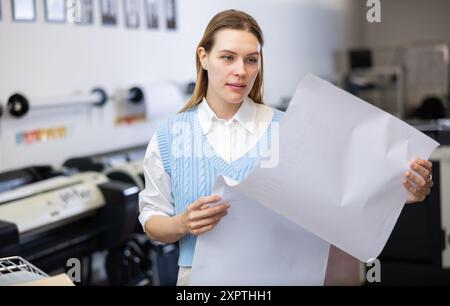 Print worker controlling printing process on modern offset machine in print shop Stock Photo