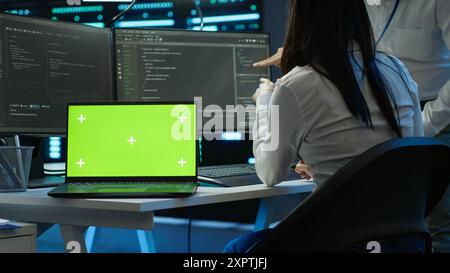 Programmer in data center managing and maintaining databases using chroma key notebook, ensuring data integrity and security. Expert updating server room systems using isolated screen laptop, camera A Stock Photo