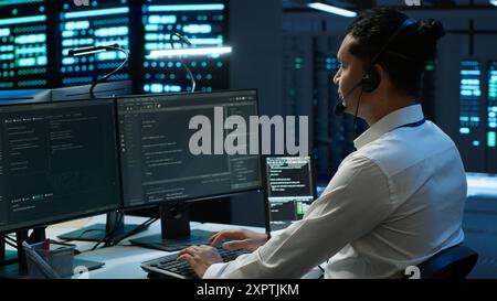 Data center agent providing logistics support to businesses and overseeing infrastructure. Server farm worker oversees hardware rackmounts and communicates with technicians, camera A Stock Photo