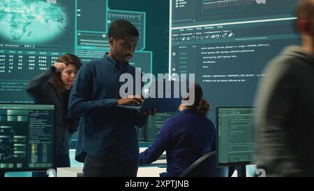Group of governmental hackers analyzing digital threats on pc networks, using a big screen. Specialists working on collecting information, fighting against cybercrime and cyberterrorism. Camera A. Stock Photo
