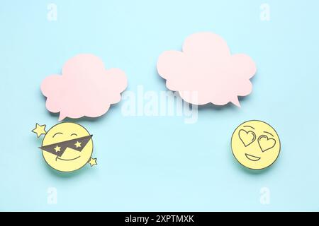 Paper faces with blank speech bubbles on blue background Stock Photo