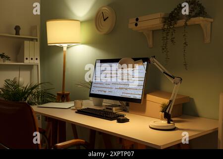 Stylish workplace of programmer with modern computers and glowing lamps in office Stock Photo