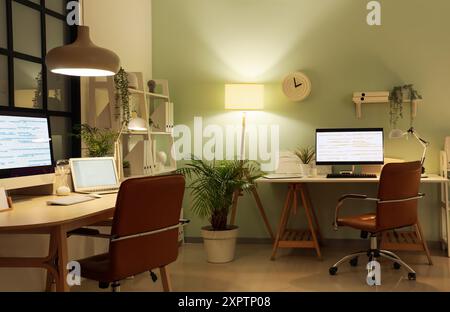 Stylish workplaces of programmer with modern computers and glowing lamps in office Stock Photo